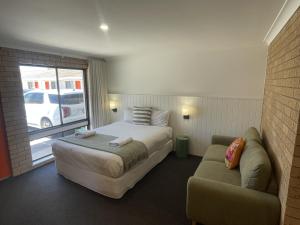 ein Hotelzimmer mit einem Bett und einer Couch in der Unterkunft Albury Allawa Motor Inn in Albury
