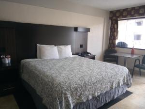 Una habitación de hotel con una cama, una mesa y una ventana. en La Bella Oceanfront Inn - Daytona, en Daytona Beach