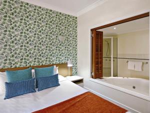 a bedroom with a bed and a bath tub at Mantra on the Inlet in Port Douglas