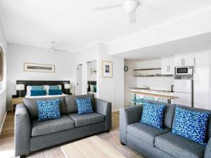 a living room with two couches and a kitchen at Mantra PortSea in Port Douglas