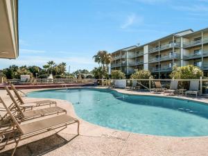 a swimming pool with lounge chairs and a building at Happy Hour Tybee in Tybee Island