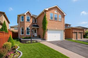 a brown brick house with a white garage at Spacious 5BR Retreat with Private Suite Sleeps 12 in Mississauga