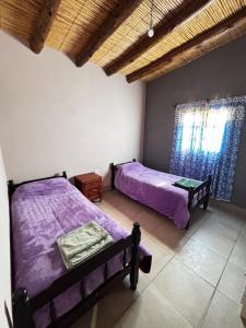 two beds in a room with purple sheets at Alojamiento Tati in Purmamarca