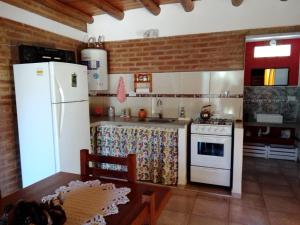 a kitchen with a white refrigerator and a stove at Aguaribay Cabañas in Arroyo de Los Patos