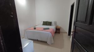 ein Schlafzimmer mit einem weißen Bett mit einer rosa Decke in der Unterkunft Casa Angela María in Caacupé