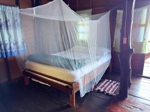 ein Himmelbett mit einem darüber liegenden Netz in der Unterkunft Ao Siri Beach Bungalow in Ko Jum