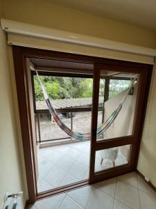 a glass door with a hammock in a room at Meu cantinho in Canela