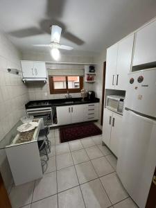 a kitchen with white appliances and a table in it at Meu cantinho in Canela +4 photos
