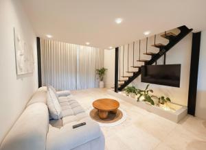 een woonkamer met een witte bank en een tv bij Maison Boheme Modern Apartment & Villa with Pool in Sanur in Sanur