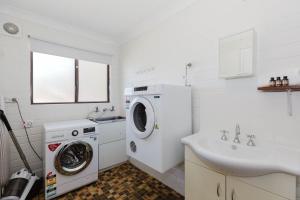 Alpha Centauri - 8 - 39 Gippsland Street في جيندابين: حمام ابيض مع غسالة ومغسلة