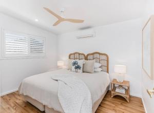 a white bedroom with a bed and a ceiling fan at The Sand Box in Kingscliff