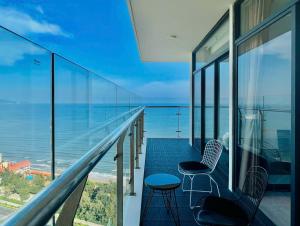 a balcony with two chairs and a view of the ocean at CSJ TOWER VŨNG TÀU - CĂN HỘ DU LỊCH NGHỈ DƯỠNG CẠNH BÃI BIỂN Po's HOMESTAY in Vung Tau
