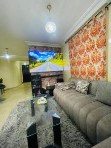 a living room with a couch and a large screen at Résidence TPM in Casablanca +6 photos