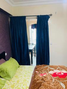 a bedroom with a bed with blue curtains and a table at Résidence TPM in Casablanca