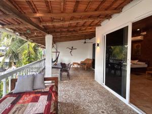 eine Veranda eines Hauses mit einem Bett und einer Terrasse in der Unterkunft Palm Breeze Suites in Palolem