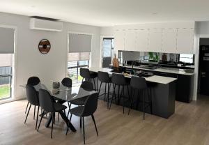 Eine Küche mit schwarzen Stühlen, einem Tisch und einer Theke in der Unterkunft Azure Abode in Broulee