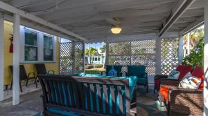 a screened in porch with a bench and chairs at 1BR 1BA NorthStar Bungalow. Just Steps to the beach and the bay. in St Pete Beach