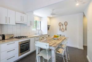 Bayshore Bungalow 12 - Oceanstays في خليج بايرون: مطبخ بخزائن بيضاء وطاولة خشبية +17 صورة