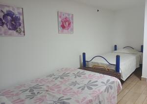 a bedroom with a bed and two pictures on the wall at El Recuerdo de Paipa, Boyacá, Colombia in El Manzano