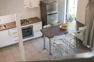 Bayshore Bungalow 13 - Oceanstays في خليج بايرون: مطبخ مع طاولة وكراسي وثلاجة