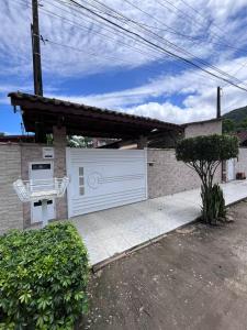 a garage with a white gate and a house at Casa da alegria in Ubatuba