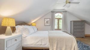 a bedroom with a white bed with a dresser and a window at Cordelia by AvantStay Amazing Backyard 10mins from Stockbridge in Lee