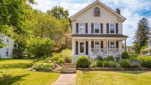 a white house with a porch and a yard at Cordelia by AvantStay Amazing Backyard 10mins from Stockbridge in Lee
