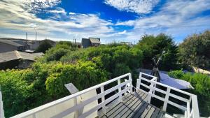 Encantadora Casa con Balcón a Pasos del Mar في لاس كروسيس: سياج أبيض أعلى شرفة بها شجيرات