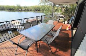 a table and chairs on a deck with a view of the water at Black Wattle Bungalow 30 Lake Bennett in Lake Bennett