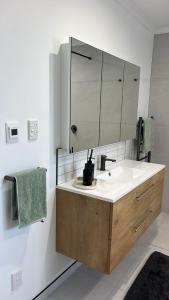un bagno con lavandino e specchio di Mount Taranaki Basecamp 4BR Farmhouse & Games Room  Altre 8 foto