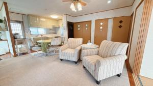 Una sala de estar con sillas y una mesa y una cocina. en Green Lodge, en Yomitan