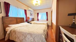 Una habitación de hotel con dos camas y un escritorio. en Green Lodge, en Yomitan