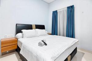a bedroom with a large white bed with blue curtains at Grace House Syariah Cikarang RedPartner in Jatirarangan
