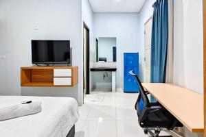 a bedroom with a desk and a bed and a television at Grace House Syariah Cikarang RedPartner in Jatirarangan
