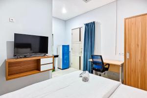a hotel room with a bed and a desk and a television at Grace House Syariah Cikarang RedPartner in Jatirarangan +10 photos