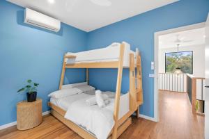 a bedroom with two bunk beds and a blue wall at Gully & Tide in Aireys Inlet