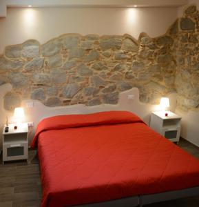 a bedroom with a red bed and a stone wall at Villa Lidia Teramo in Teramo