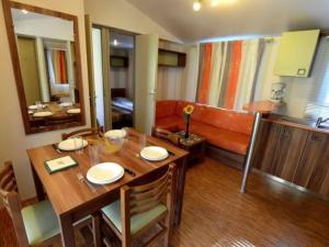 a dining room with a table and a couch at Mobil home avec Terrasse - 3 Chambres, 6 Personnes - API-1-52-896 in Saint-Rome-de-Tarn