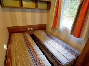 a couple of beds in a room with a window at Mobil home avec Terrasse - 3 Chambres, 6 Personnes - API-1-52-896 in Saint-Rome-de-Tarn +13 photos