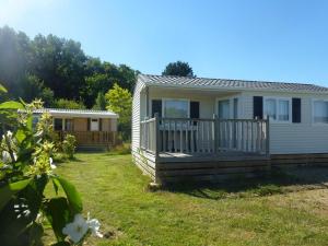 uma pequena casa branca com um alpendre e um quintal em Mobil home avec terrasse à Loudéac pour 4 personnes - API-1-52-898 em Loudéac mais 6 fotografias