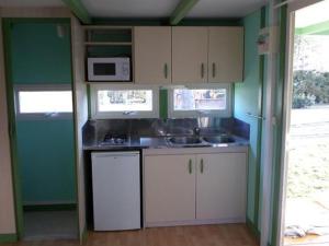 a small kitchen with white cabinets and a microwave at Chalet confortable avec terrasse - 4 personnes - API-1-52-923 in La Chapelle