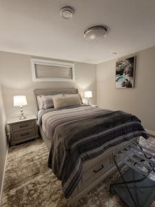 a bedroom with a large bed and two lamps at Elegance by Mal and Al Luxury Private Bsmt Suite in Regina