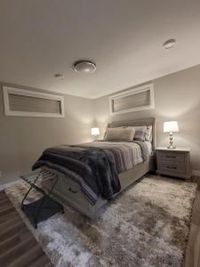 a bedroom with a bed with two lamps and a rug at Elegance by Mal and Al Luxury Private Bsmt Suite in Regina