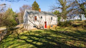 een oud wit huis met een rode deur in een tuin bij Sage & Stone Cottage in Lynchburg