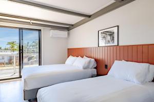 two beds in a room with a window at Black Dolphin Motel in Merimbula