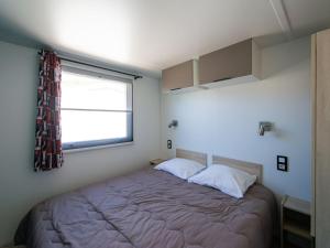 a small bedroom with a bed with a window at Mobil-home confortable avec terrasse pour 5 personnes - API-1-52-916 in Saint-Rome-de-Tarn +14 photos
