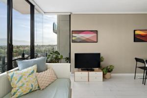 a living room with a couch and a flat screen tv at Ocean view apartment close to CBD with indoor pool. in Melbourne