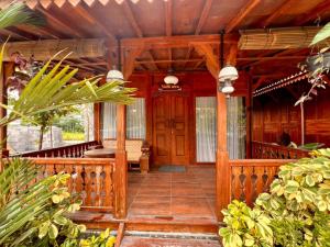 un portico di una casa di legno con una ringhiera di legno di Nglaras Resort Yogyakarta a Ngaglik
