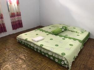 a bed with a green comforter with flowers on it at NATA homestay in Banggai