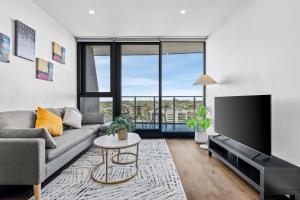 Galleria on the Glen - High floor deluxe apartment في غلين وافرلي: غرفة معيشة مع أريكة وتلفزيون